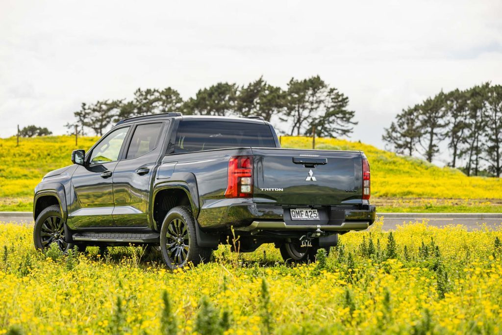 2024 Mitsubishi Triton VRX 4X4 rear quarter shot, parked among yellow flowers