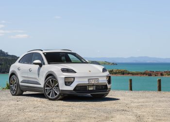 Porsche-Macan 4 EV in white, parked cliffside in front of a harbour