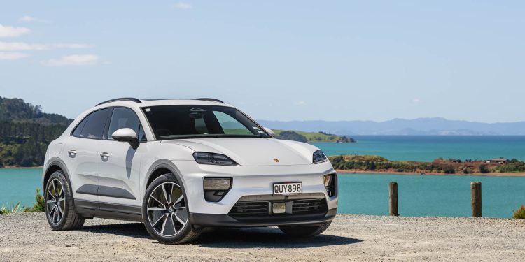 Porsche-Macan 4 EV in white, parked cliffside in front of a harbour