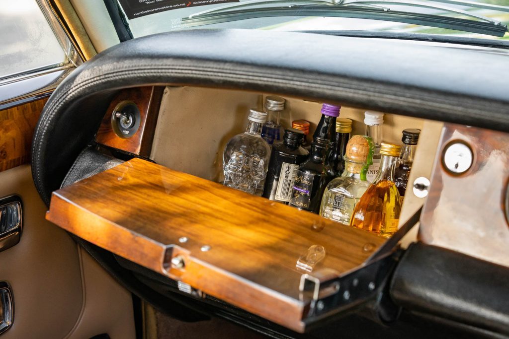 Liquor stash inside the Rolls, with a map light switch, and wooden glovebox door