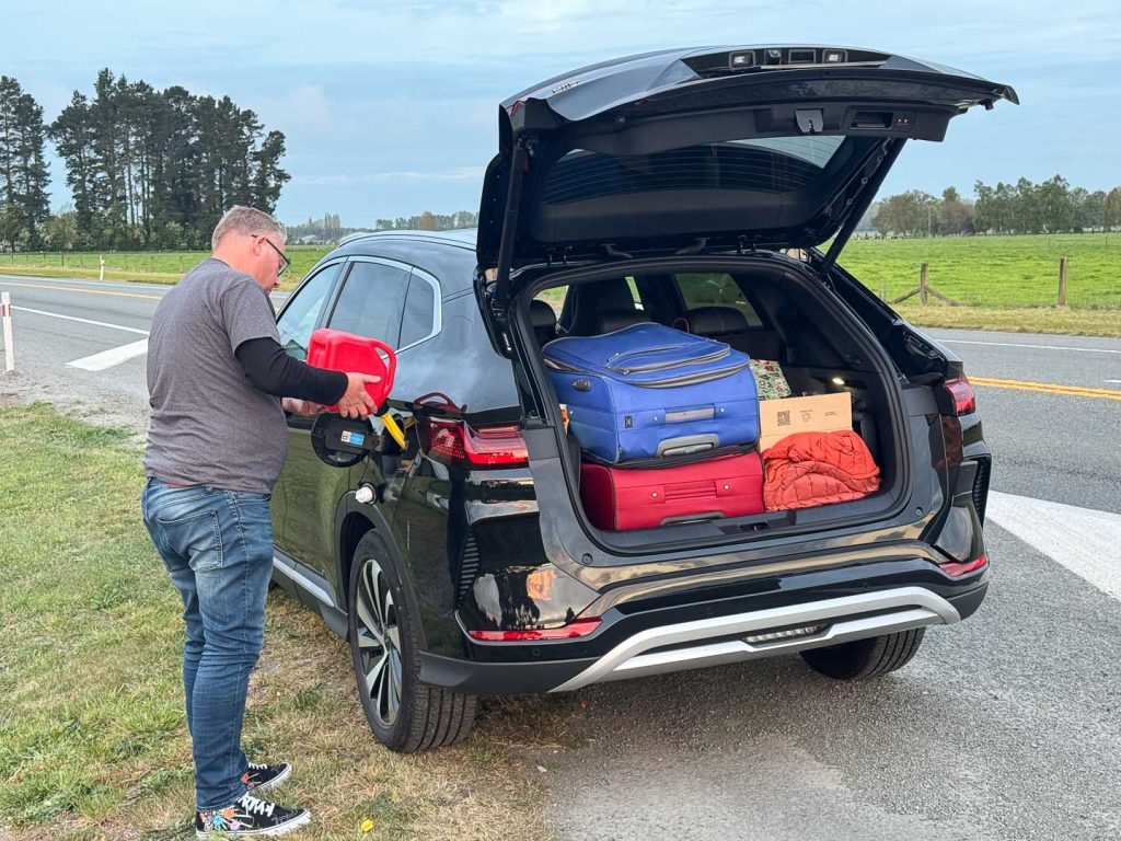 Man filling up BYD filled with luggage in the back