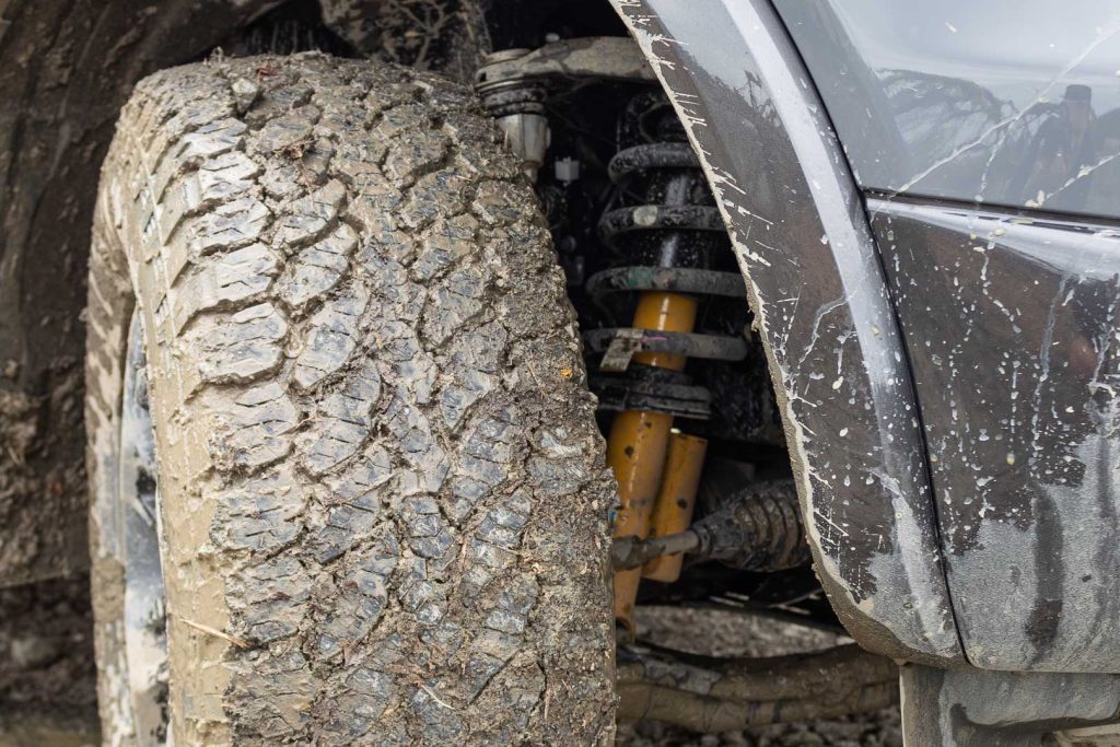 thick mud caked on off-road tyres, with yellow off-road suspension shown