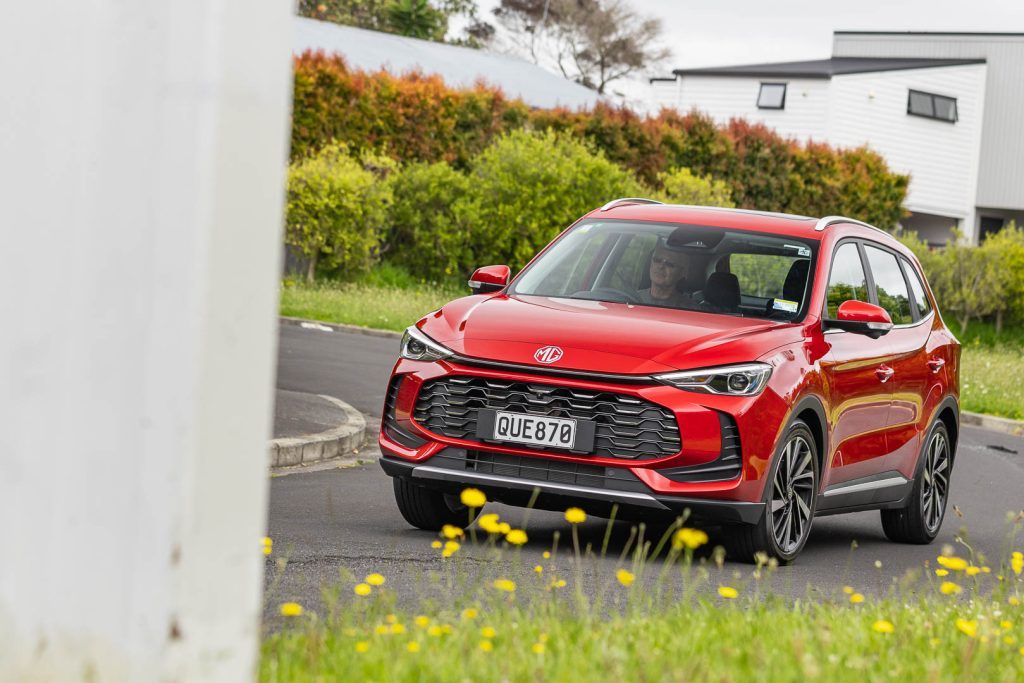 Cornering shot of red SUV hybrid with wild flowers