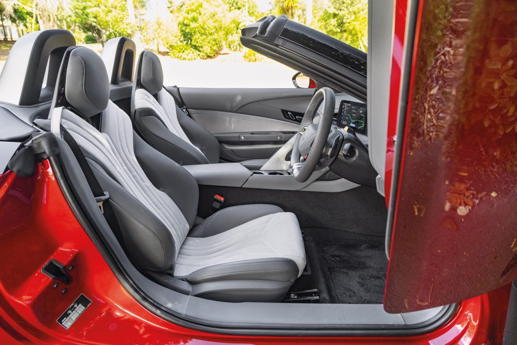 Interior of a red MG Cyberster convertible with black and light gray seats, sleek dashboard, and digital display screen