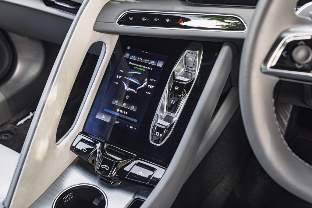 Modern car interior center console with a touchscreen display showing climate control settings and gear selector buttons arranged vertically