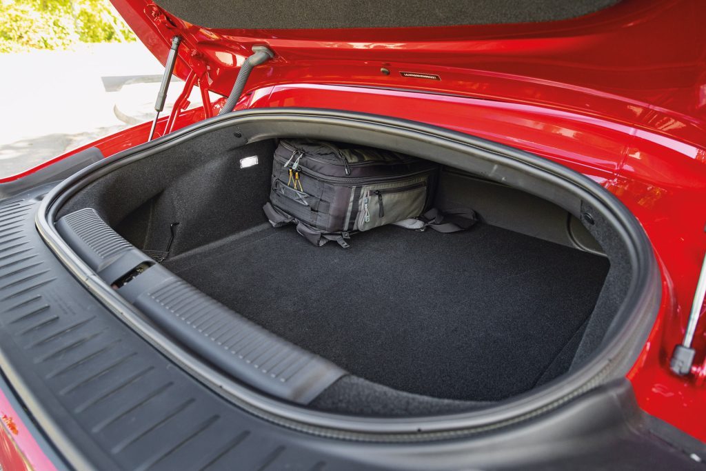 Open trunk of a red MG Cyberster with a black and gray backpack inside, showcasing the spacious and clean interior