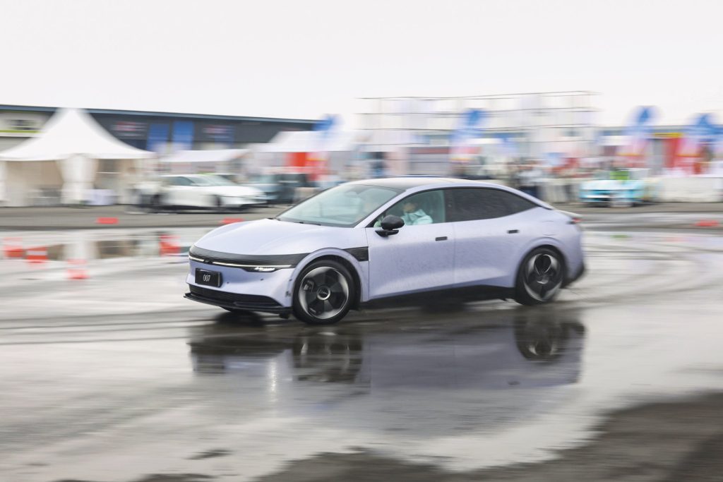 Zeekr car drifting on a wet track with a blurred background of tents and other vehicles