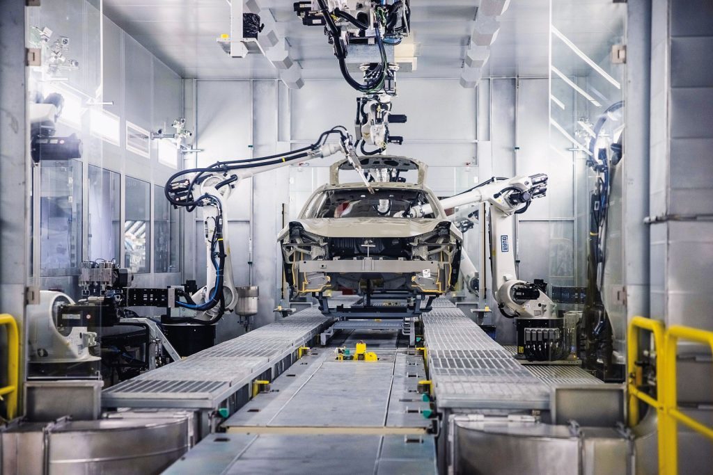 Automated car manufacturing facility with robotic arms assembling a car chassis