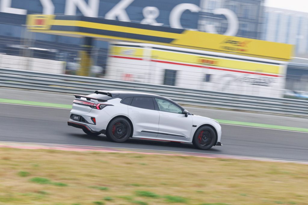 White Zeekr sports car with black and red accents driving on a racetrack with a prominent rear spoiler