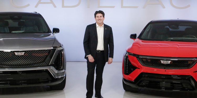 John standing next to a couple of Cadillacs that are coming to NZ